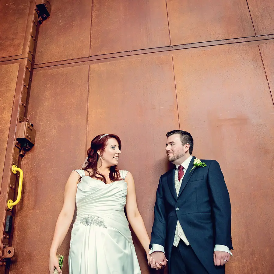 Bride and groom holding hands in front of Worcester architecture